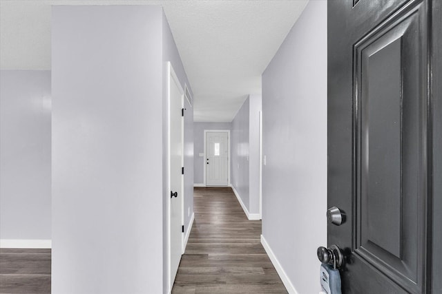 hallway with dark hardwood / wood-style flooring and a textured ceiling