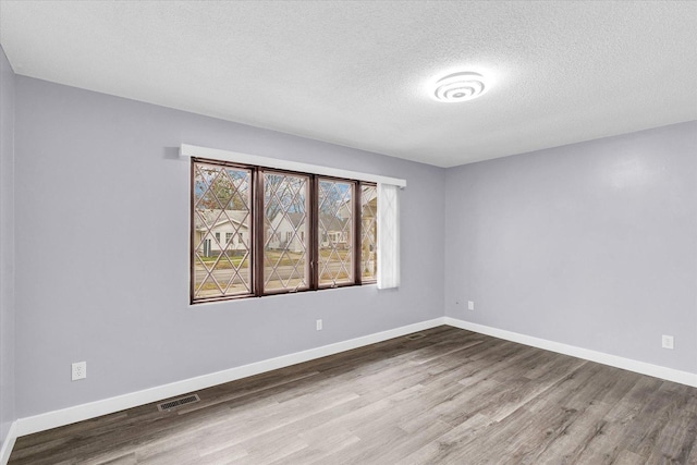 spare room featuring a textured ceiling and hardwood / wood-style flooring