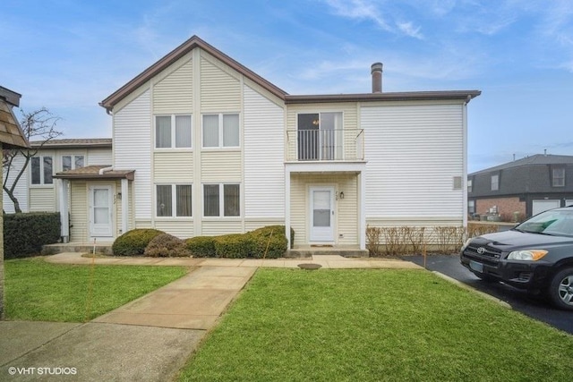 view of front facade with a front yard and a balcony