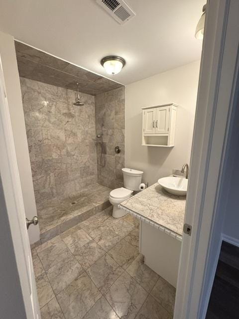 bathroom with vanity, toilet, and tiled shower