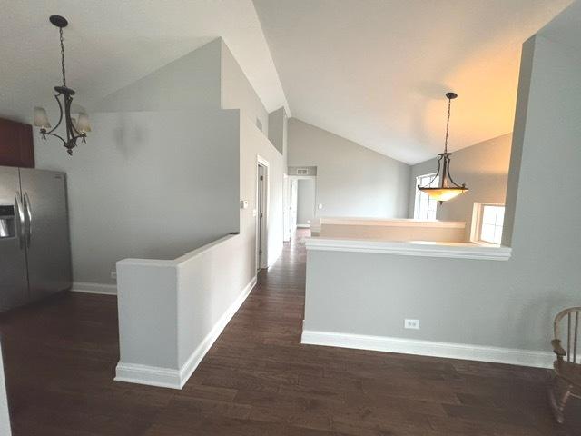 kitchen featuring dark hardwood / wood-style flooring, a notable chandelier, stainless steel fridge with ice dispenser, hanging light fixtures, and lofted ceiling