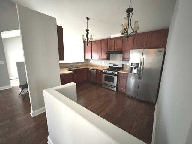 kitchen featuring sink, dark hardwood / wood-style floors, a chandelier, pendant lighting, and appliances with stainless steel finishes