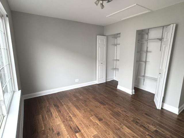 unfurnished bedroom featuring multiple windows, dark hardwood / wood-style flooring, and a closet