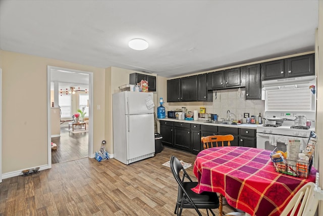 kitchen featuring backsplash, light wood-type flooring, white appliances, and sink