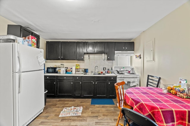 kitchen with white appliances, backsplash, electric panel, sink, and hardwood / wood-style flooring