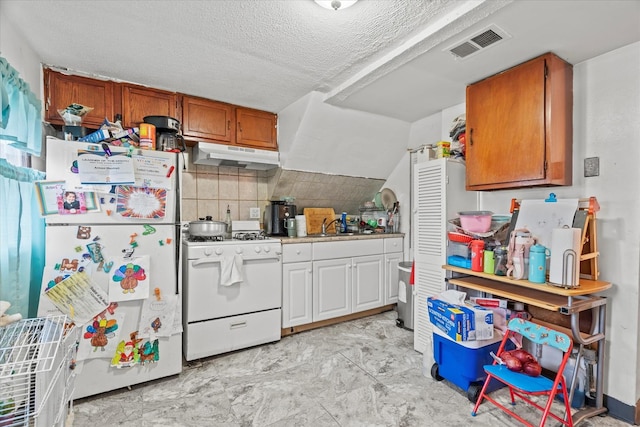 kitchen with a textured ceiling, decorative backsplash, and white appliances