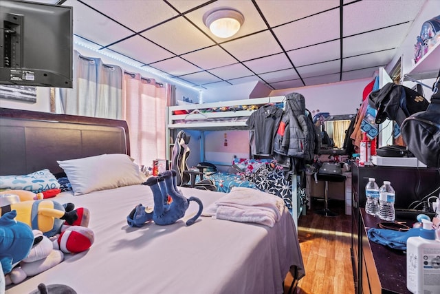 bedroom with a paneled ceiling and hardwood / wood-style flooring