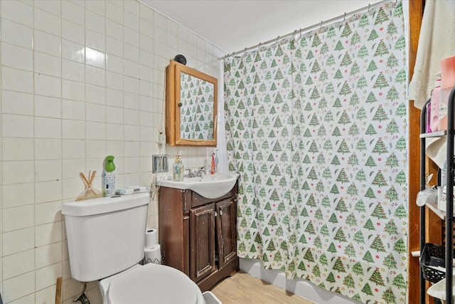 bathroom with toilet, vanity, tile walls, and hardwood / wood-style flooring