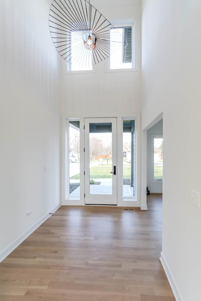 foyer entrance featuring plenty of natural light, light wood-type flooring, and a towering ceiling