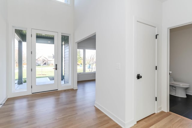 entryway featuring a towering ceiling and light wood-type flooring