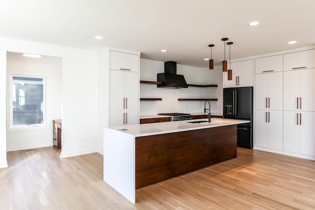 kitchen with exhaust hood, black refrigerator with ice dispenser, light hardwood / wood-style flooring, and pendant lighting