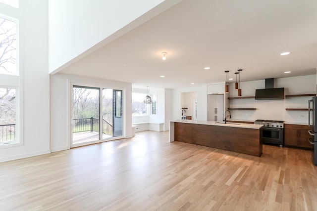 kitchen featuring a healthy amount of sunlight, high end appliances, an island with sink, and range hood