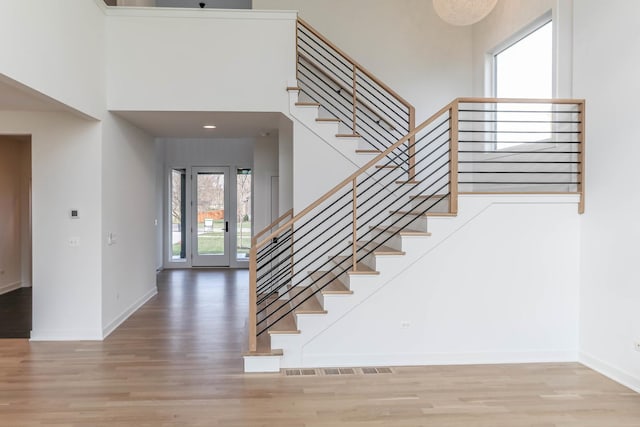 staircase with wood-type flooring and a high ceiling