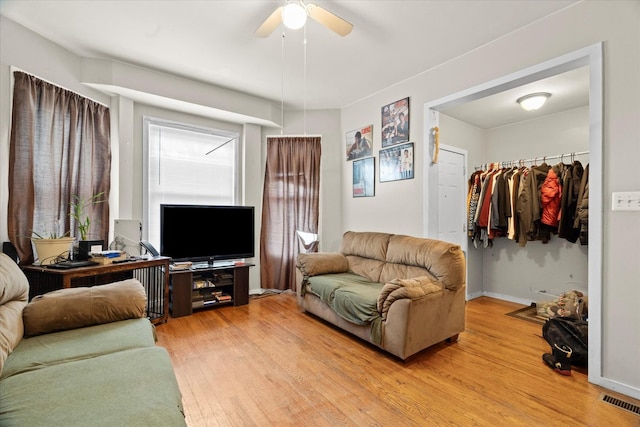 living room featuring light wood-type flooring, ceiling fan, and a healthy amount of sunlight