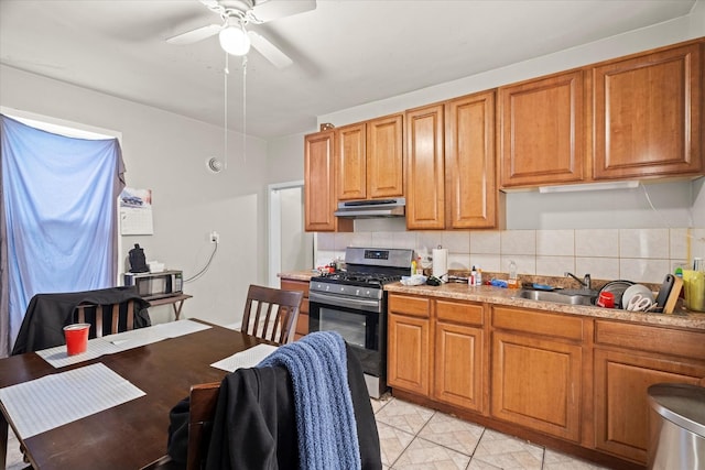 kitchen featuring sink, gas range, ceiling fan, tasteful backsplash, and light tile patterned flooring