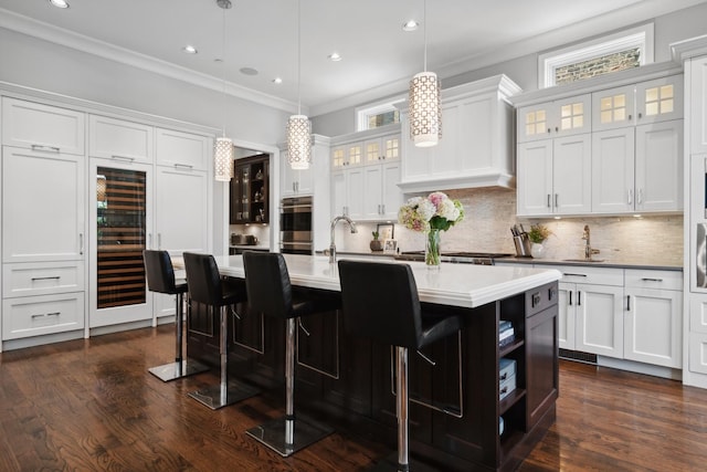 kitchen featuring a kitchen island with sink, dark hardwood / wood-style flooring, white cabinets, and pendant lighting