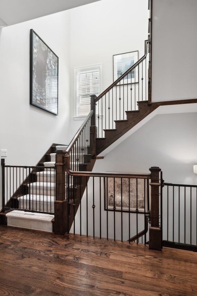 staircase with a high ceiling and hardwood / wood-style flooring