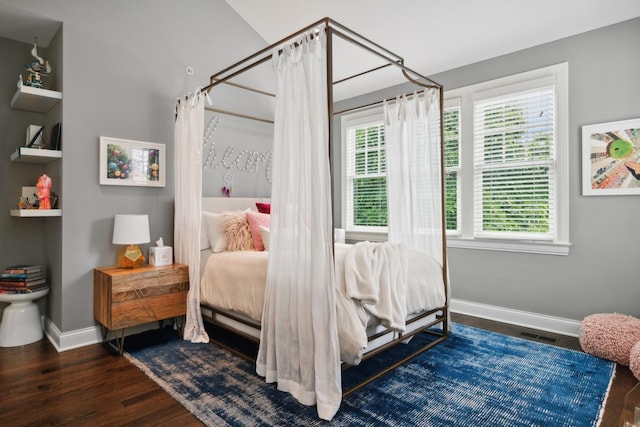 bedroom with multiple windows and dark wood-type flooring