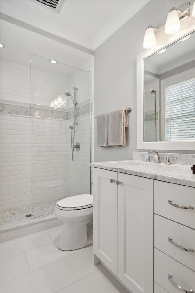 bathroom with ornamental molding, a tile shower, vanity, tile patterned flooring, and toilet