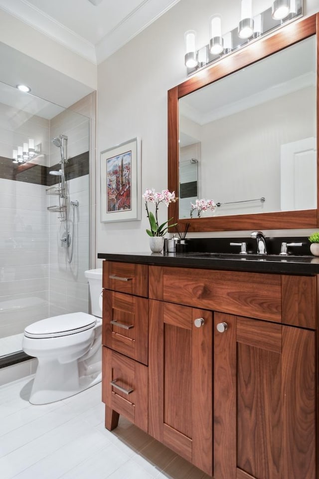 bathroom with a tile shower, vanity, toilet, and crown molding