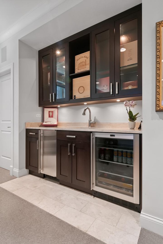 bar with crown molding, wine cooler, dark brown cabinets, light tile patterned flooring, and stainless steel refrigerator