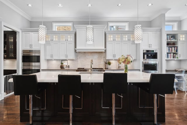 kitchen with double oven, a large island, white cabinets, and pendant lighting