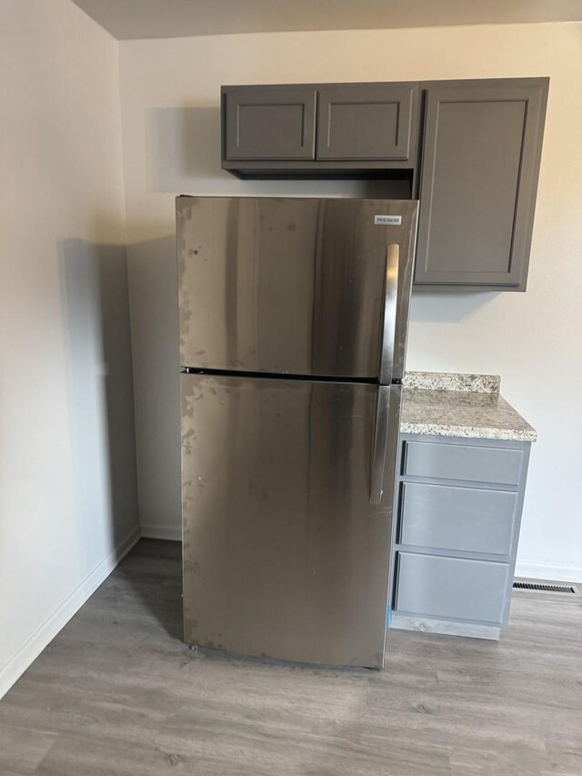 kitchen with light countertops, light wood finished floors, freestanding refrigerator, and gray cabinetry