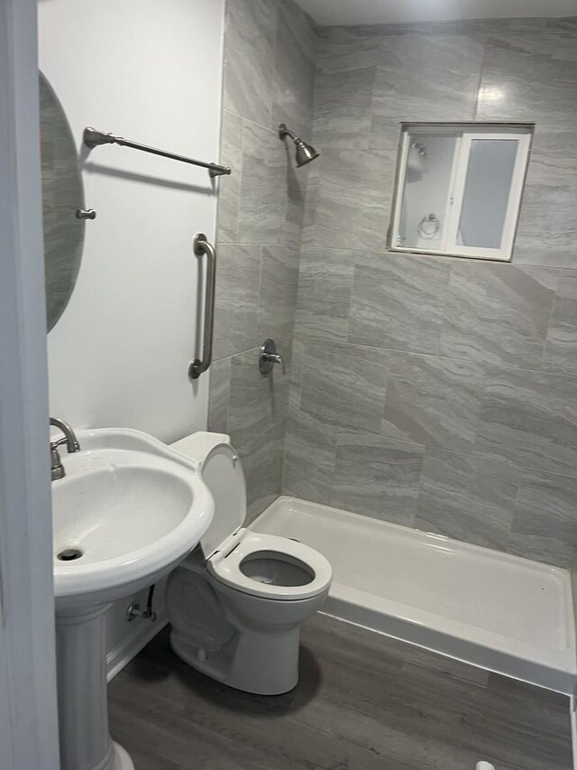 full bathroom featuring a sink, a shower stall, toilet, and wood finished floors