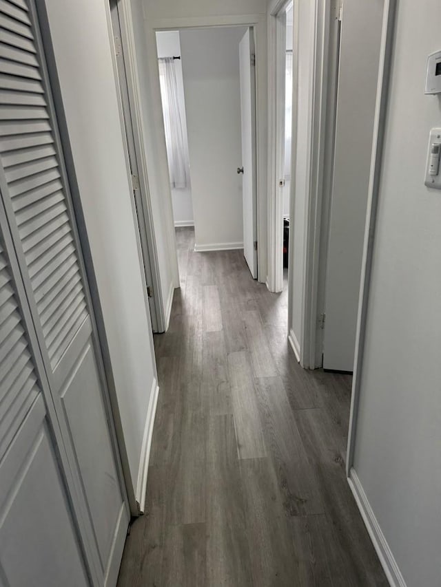 hallway featuring dark wood-style floors and baseboards