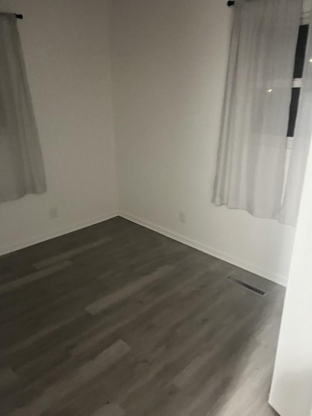 unfurnished room with baseboards and wood finished floors