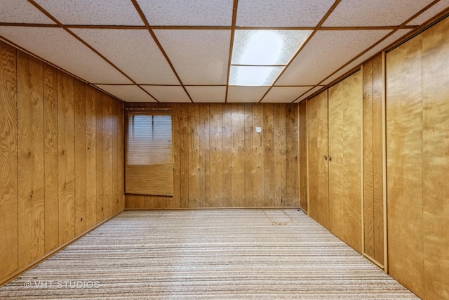 interior space featuring a paneled ceiling and wood walls