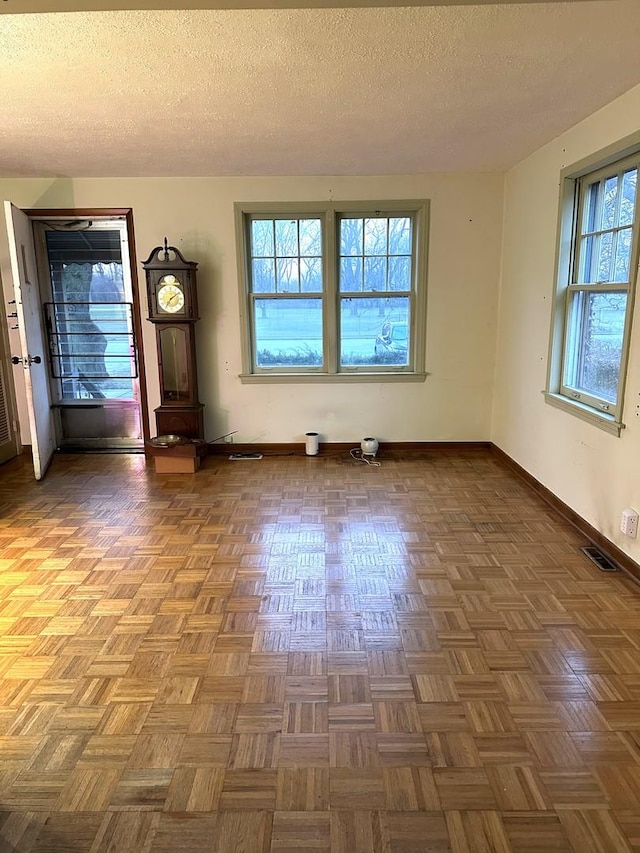 empty room with dark parquet floors and a textured ceiling