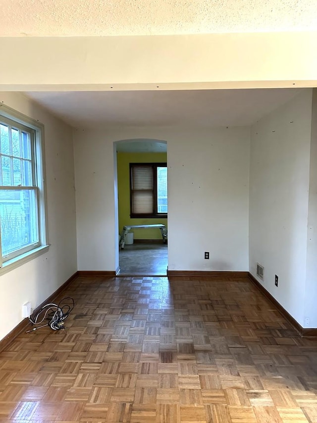 unfurnished room with parquet flooring and a textured ceiling