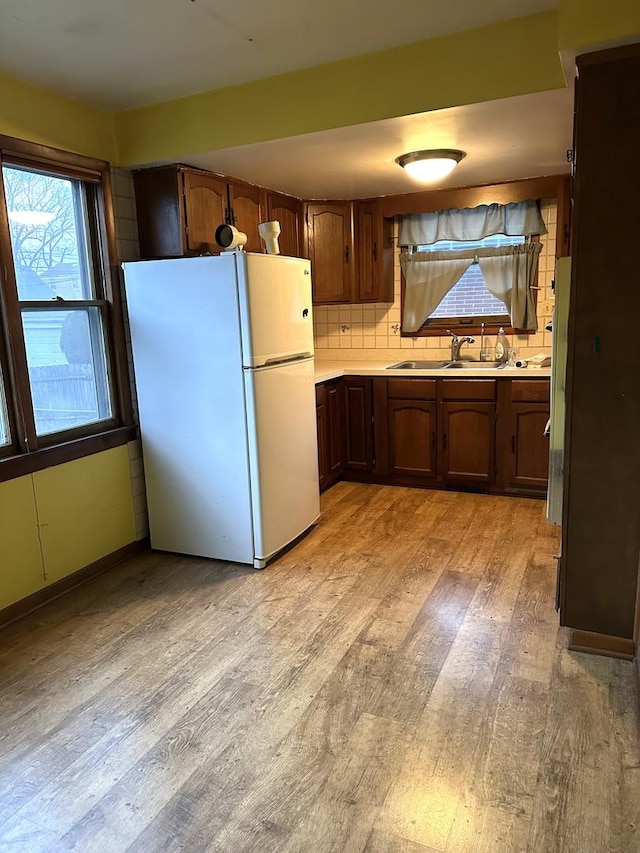 kitchen featuring white fridge, light hardwood / wood-style floors, sink, and tasteful backsplash