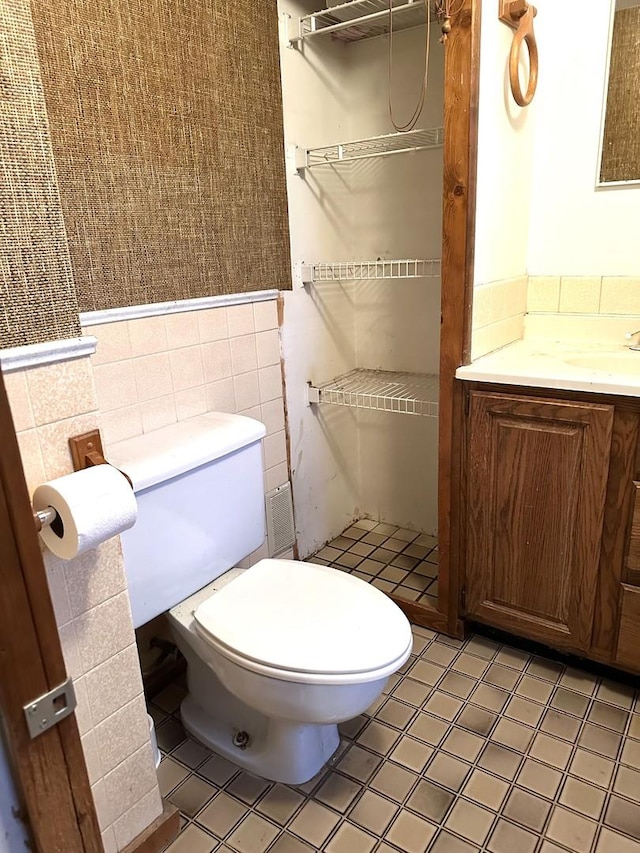 bathroom featuring vanity, toilet, and tile walls