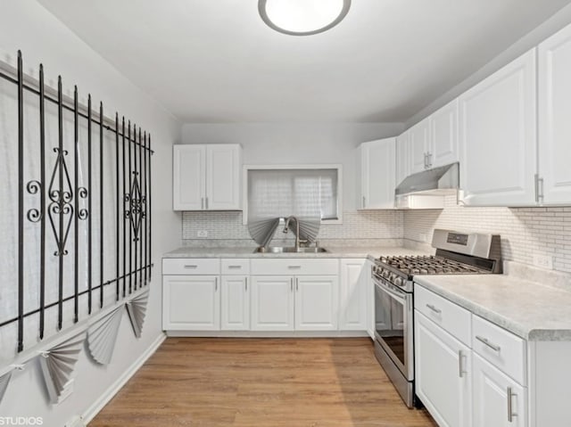 kitchen featuring white cabinets, sink, gas range, light wood-type flooring, and tasteful backsplash