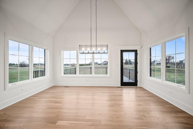 unfurnished sunroom featuring a wealth of natural light, a chandelier, and vaulted ceiling