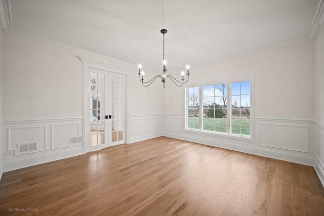 unfurnished dining area with a chandelier, hardwood / wood-style flooring, and crown molding