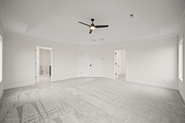 carpeted spare room with a raised ceiling, ceiling fan, and ornamental molding