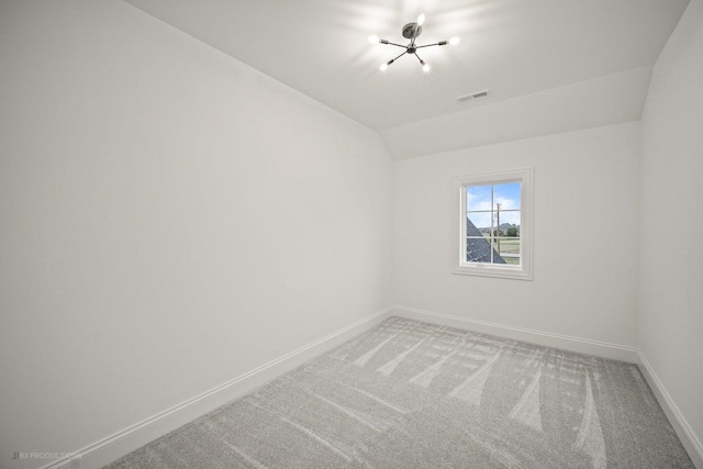 spare room with carpet and vaulted ceiling