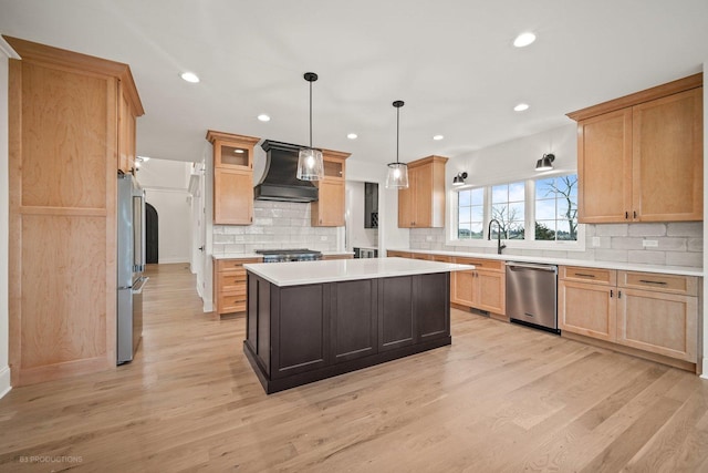 kitchen featuring stainless steel appliances, light hardwood / wood-style floors, decorative light fixtures, a kitchen island, and custom range hood