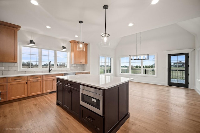 kitchen with a wealth of natural light, stainless steel appliances, and hanging light fixtures