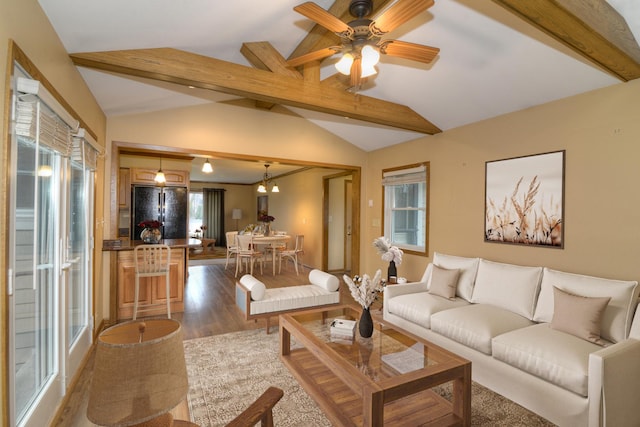 living room with vaulted ceiling with beams, plenty of natural light, and light wood-type flooring