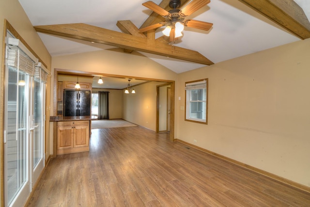 unfurnished living room featuring vaulted ceiling with beams and a wealth of natural light