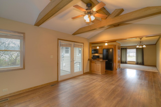 unfurnished living room featuring vaulted ceiling with beams, a wealth of natural light, light hardwood / wood-style flooring, and ceiling fan with notable chandelier