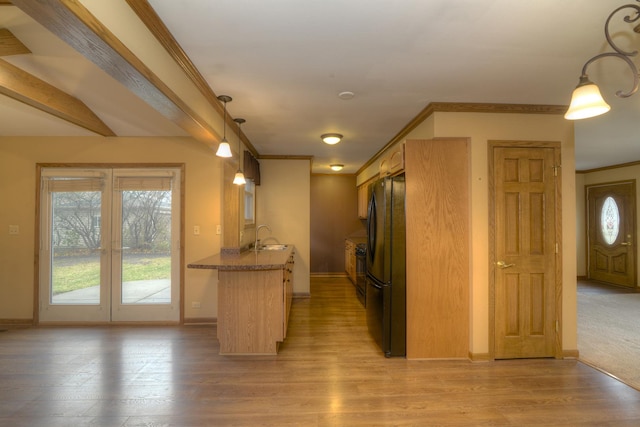 kitchen with kitchen peninsula, light wood-type flooring, decorative light fixtures, and black fridge