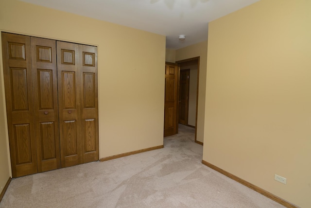 unfurnished bedroom with light carpet and a closet