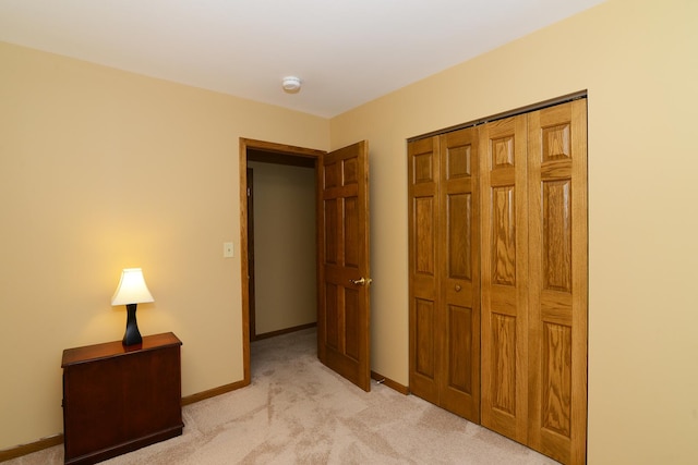 unfurnished bedroom with light colored carpet and a closet