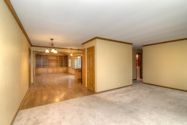 unfurnished room featuring light wood-type flooring, ornamental molding, and a chandelier