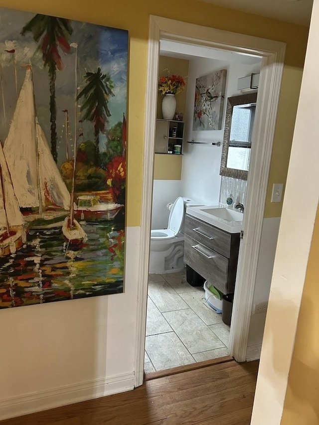 bathroom featuring wood-type flooring, vanity, and toilet